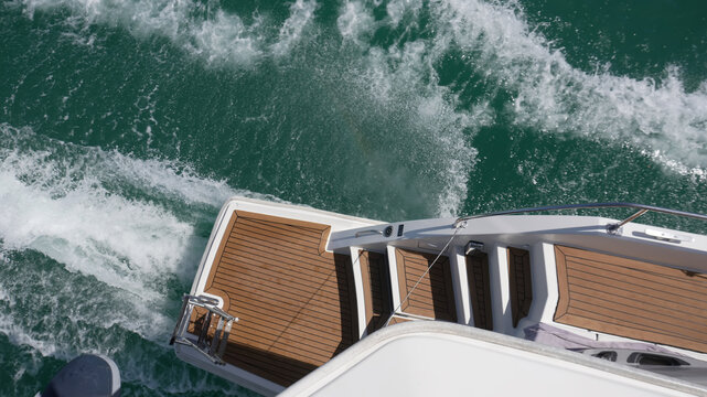 Luxury yacht in motion on the sea. View from the deck teak wood and the stern of the yacht in motion