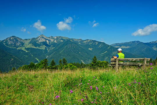 Man sitting on bench enjoying mountain view in Chiemgau Alps Bavaria