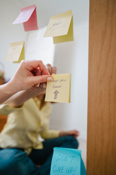 Hand placing positive affirmation sticky note on mirror for mindfulness