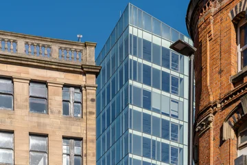 Modern glass office building between historic brick facades in Manchester, England, UK © Bernd Brueggemann