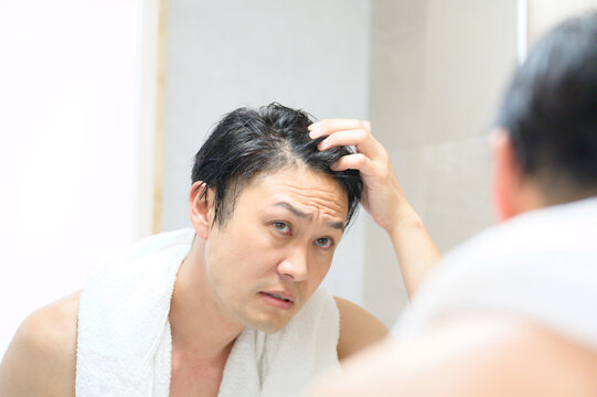 鏡で髪の毛を気にする日本人男性