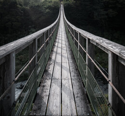 Perspective view of a weathered footbridge over a river canyon