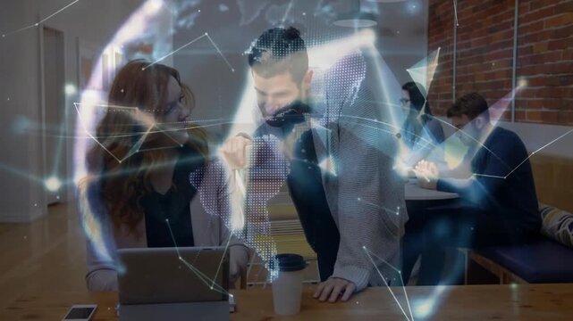 woman typing on laptop and man pointing at screen in tech coworking hub, showing holographic globe