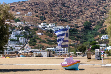 View of a Greek national flag next to a colourful decorated boat at the Mylopotas beach in Ios Greece