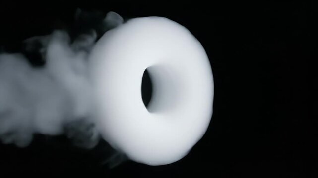 white smoke ring across black background; soft vapor trail, donut shape, high-contrast studio lighting, slow cinematic motion, minimal composition, isolated on black, ideal for looping visual effects,