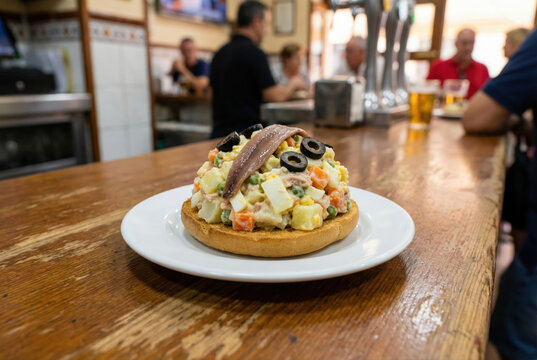 Tapa de marinera servida sobre una base de pan tostado con anchoa y aceitunas negras en la barra de un bar tradicional de Murcia