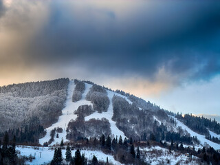 Mystical snowy Carpathian peaks under cloudy skies in the sunny weather