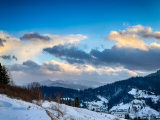 Mystical snowy Carpathian peaks under cloudy skies in the sunny weather