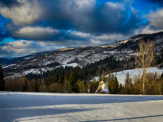 Mystical snowy Carpathian peaks under cloudy skies in the sunny weather