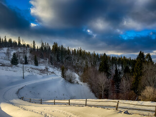 Mystical snowy Carpathian peaks under cloudy skies in the sunny weather