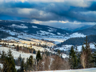 Mystical snowy Carpathian peaks under cloudy skies in the sunny weather