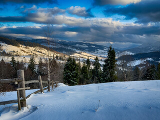 Mystical snowy Carpathian peaks under cloudy skies in the sunny weather