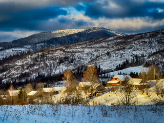 Mystical snowy Carpathian peaks under cloudy skies in the sunny weather