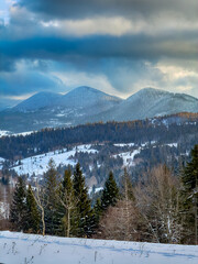 Mystical snowy Carpathian peaks under cloudy skies in the sunny weather