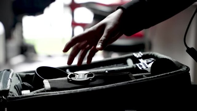 Person's hands organizing equipment inside a camera bag, preparing for a trip