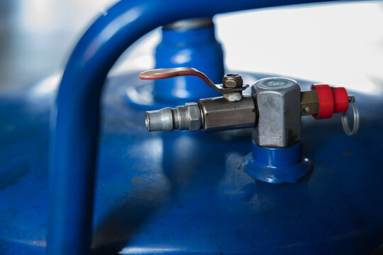Close-up of blue portable air compressor tank safety relief valve and quick coupler fitting mechanism in auto repair garage, Auto repair shop, Garage, Workshop, Pneumatic system, Air compressor