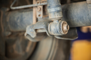 Close-up of dirty car suspension rubber bushing and metal arm link under vehicle chassis in auto repair garage workshop, Auto repair shop, Garage, Workshop, Car maintenance, Suspension repair