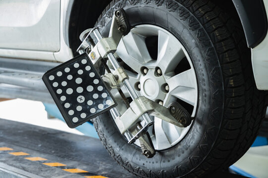 Close-up of 3D wheel alignment target sensor clamped to car alloy wheel for steering and suspension adjustment in auto repair garage, Accuracy Technology Calibration, Car maintenance inspection