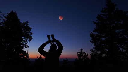 Fototapeta premium Amateur astronomer using binoculars for observing stars, planets, Moon and other celestial objects.