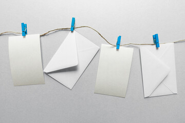 Envelopes and cards hanging with blue clothespins, gray background