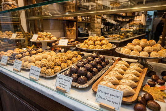 Vitrina de pasteler&iacute;a artesana con una amplia selecci&oacute;n de panellets de pi&ntilde;ones, coco tostado, mazap&aacute;n de almendra y chocolate decorada con casta&ntilde;as y hojas de oto&ntilde;o