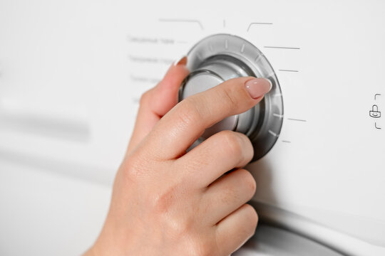 A woman's hand sets the wash cycle in a washing machine