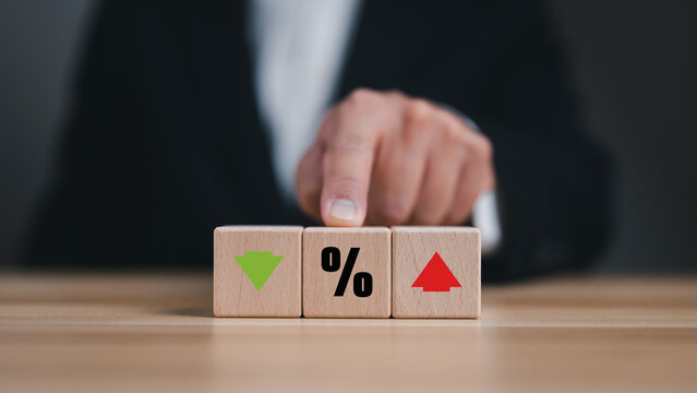 Financial interest rate concept with wooden cubes showing percent, increase and decrease, Businessman managing investment risks, mortgage rates or inflation trends.