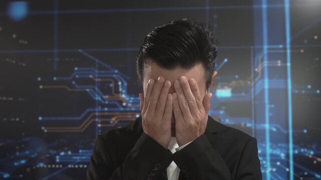Stressed Asian businessman covering face with hand against futuristic digital background, expressing frustration, burnout, pressure, emotional challenge in environment driven by advanced technology