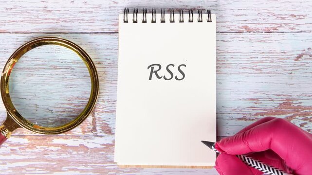 Watch as RSS is gradually written on a notepad next to a magnifying glass. Later, a hand in a pink glove traces RSS with a pen