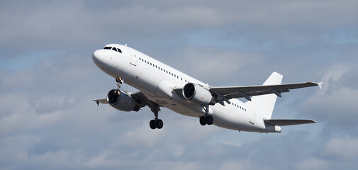 Fototapeta premium Airplane take off on the blue sky, with white clouds. Aircraft flying on sky background. White passenger jet plane in the blue sky. Low angle view of Airplane flying under blue sky, with white clouds