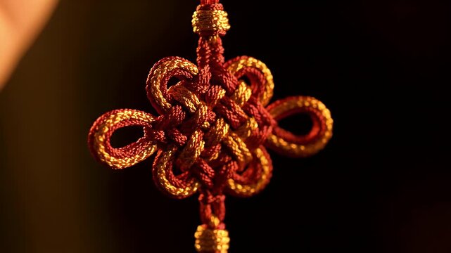 Intricate Red Gold Auspicious Knotwork Charm Macro. Delicate Silk Patterns in Warm Golden Light