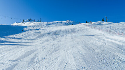 Steep alpine ski slope with groomed snow, safety fencing, and lift infrastructure, suitable for winter sports, resort marketing, and alpine tourism concepts