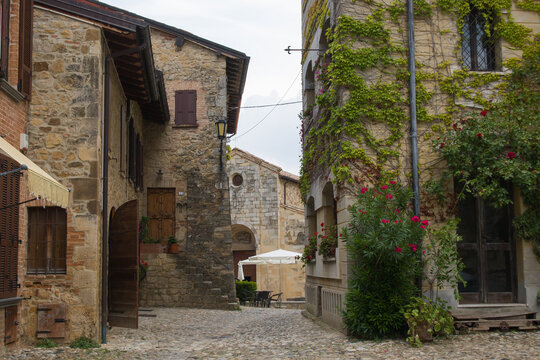 Cobbled square of the well-preserved medieval Vigoleno village in Emilia-Romagna, Italy, featuring stone fountain, ancient walls, and tower