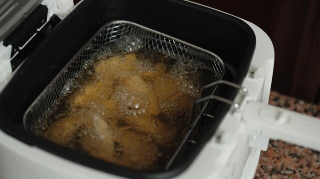 Close up of codfish fritters frying in deep fryer basket