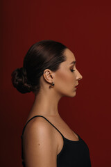 A beautiful woman's profile portrait on a dark red background. Woman, side view. Evening look and beauty concept. © Асель Иржанова
