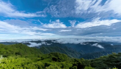 Fototapeta premium Lush green mountains shrouded in mist under a vibrant blue sky.