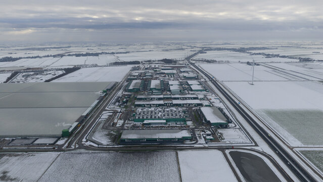 Aerial view of a sprawling industrial complex, its rooftops contrasting with the snow-covered fields, Datacenter Middenmeer, North Holland, Netherlands.