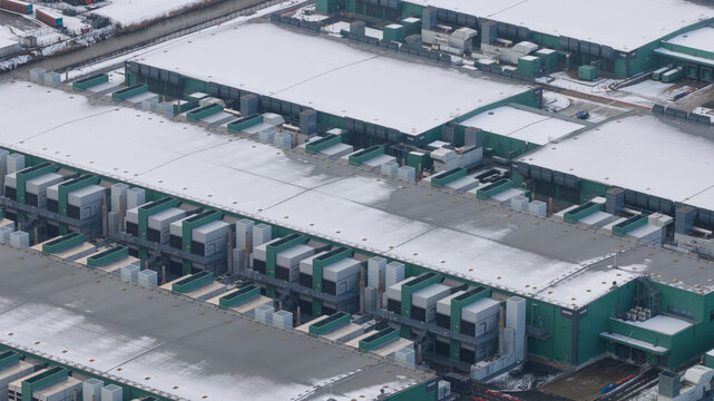 Aerial view of snow-dusted rooftops and orderly rows of buildings create a stark contrast against the muted winter landscape, Middenmeer, North Holland, Netherlands.