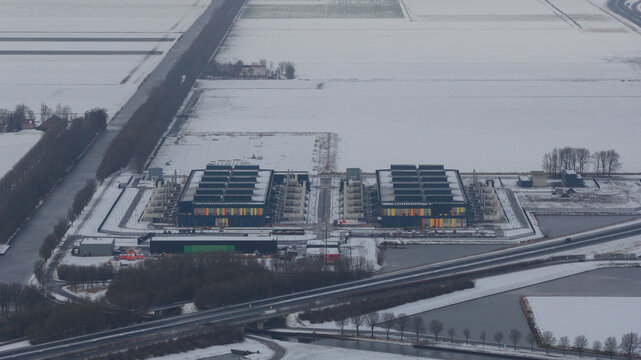 Aerial view of the symmetrical datacenter reflecting the winter light amidst the snow-covered landscape, Datacenter Middenmeer, North Holland, Netherlands.