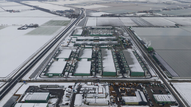 Aerial view of a datacenter with geometric precision and snow-dusted roofs, a stark contrast to the surrounding white fields, Middenmeer, North Holland, Netherlands.