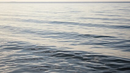 Calm ocean waves gently rippling on a serene body of water with subtle sunlight reflections on the surface with peaceful and nature and landscape