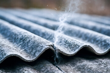 CRACKED ASBESTOS ROOF SHEET RELEASING FINE TOXIC FIBERS INTO THE AIR - Conceptual image representing health hazard, pollution, and material degradation