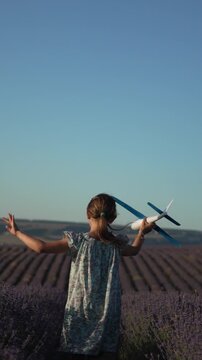 Girl airplane lavender field running through rows enjoying freedom under blue sky at sunset. Vertical video.