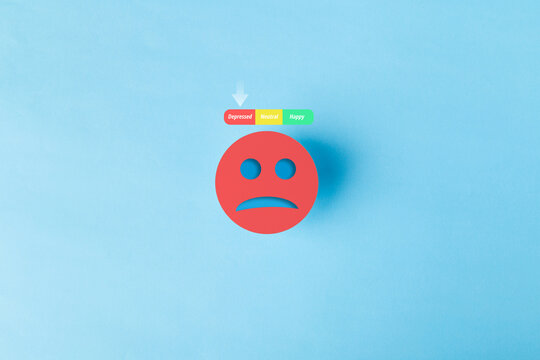 Red sad face icon with a mental health mood tracker showing depressed status on blue background. Concept for depression, burnout, psychological distress, and emotional wellness evaluation.