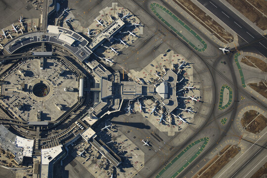 San Francisco, United States - 11 September 2018: Aerial view of the airport's geometric layout, planes casting sharp shadows on the concrete, creating a stark contrast of light and dark textures.
