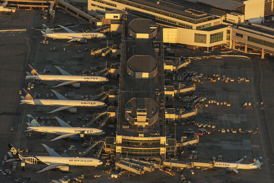 San Francisco, United States - 07 July 2024: Aerial view of a vibrant airport terminal bathed in the warm glow of sunset, with planes lined up like gleaming birds ready for flight.