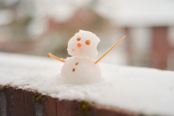 Obraz premium Tiny Snowman on Balcony Edge with Street in Background 