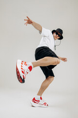 Full body shot of a stylish male dancer performing dynamic moves. Low angle wide-angle perspective emphasizes motion, energy and modern street dance style in studio. © VlaDee