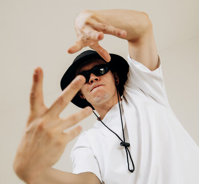 Portraits of a stylish young male dancer showing expressive dance gestures. Shot with a wide-angle lens, modern streetwear style, dynamic studio photography.