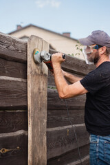 Man work on holiday repairing and renovating a country house - summer chores in the backyard and garden - power tool work